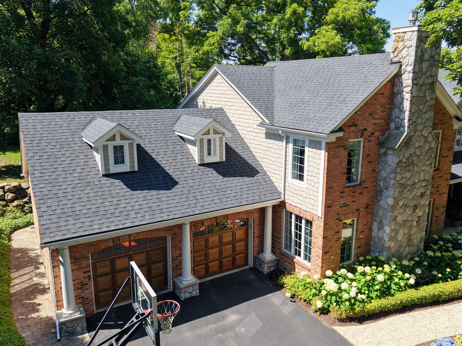 Get-R-Done Roofing completed project in Bloomfield Hills, Michigan — new architectural shingle roof + gutters on 2-story brick home with stone chimney and dormers